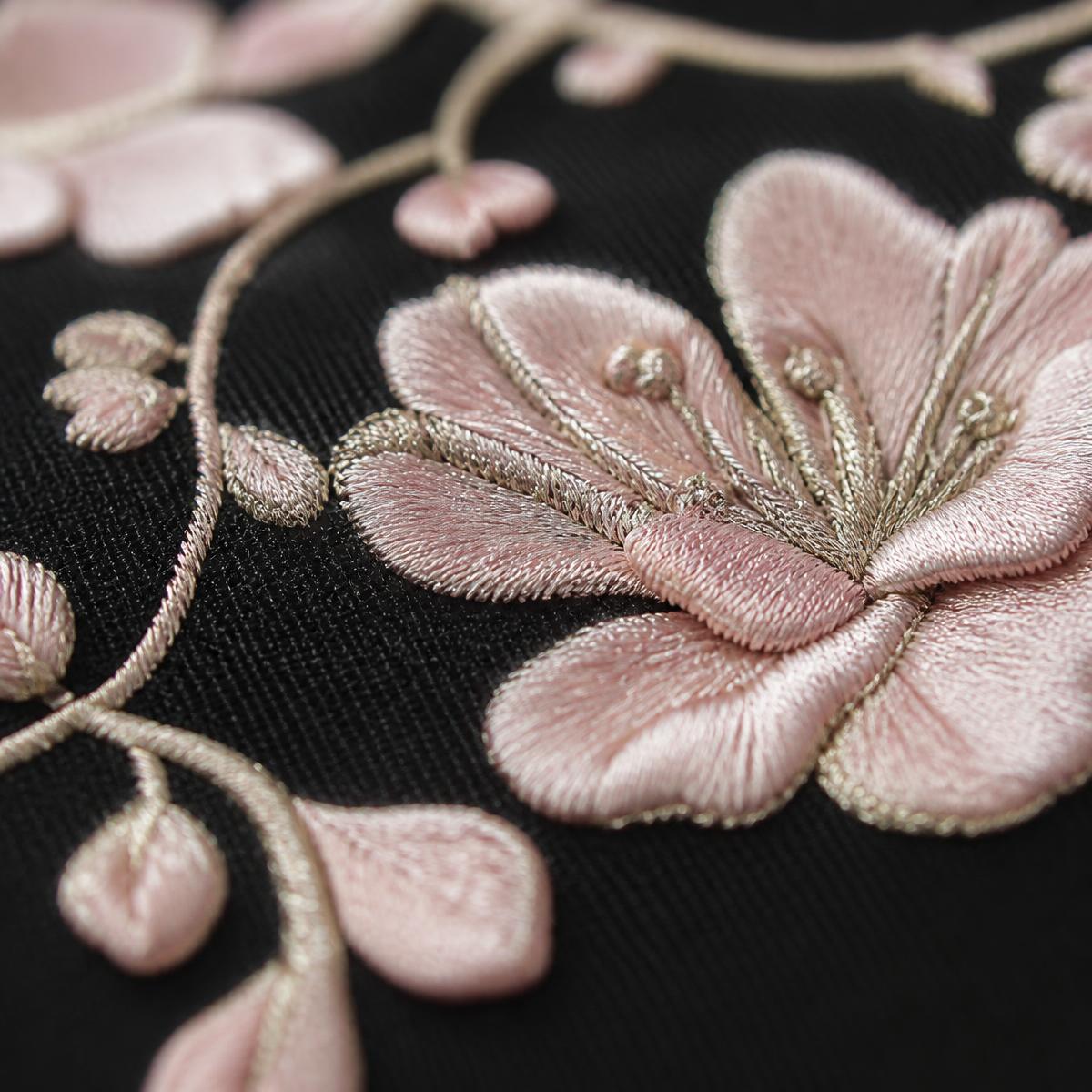 Close-up of pale pink floral embroidery with metallic-looking thread